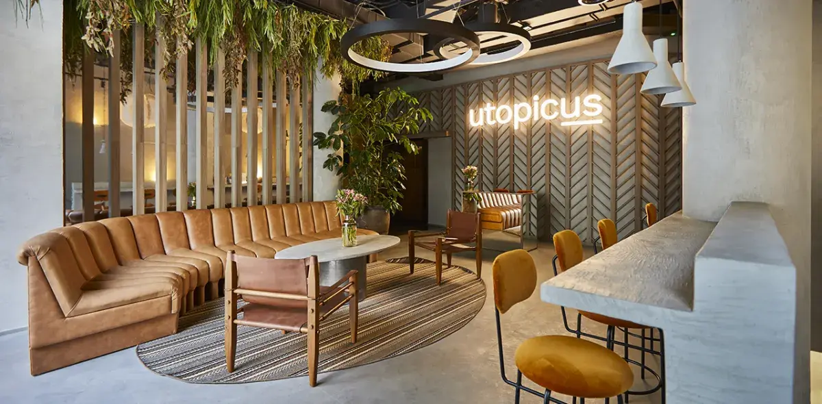 Un sofá curvo color marrón en una sala moderna con plantas colgantes.