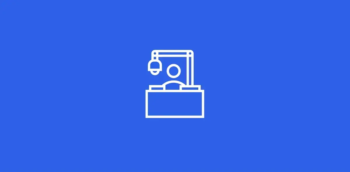 Icono de una computadora con webcam encima de un escritorio, en fondo azul.