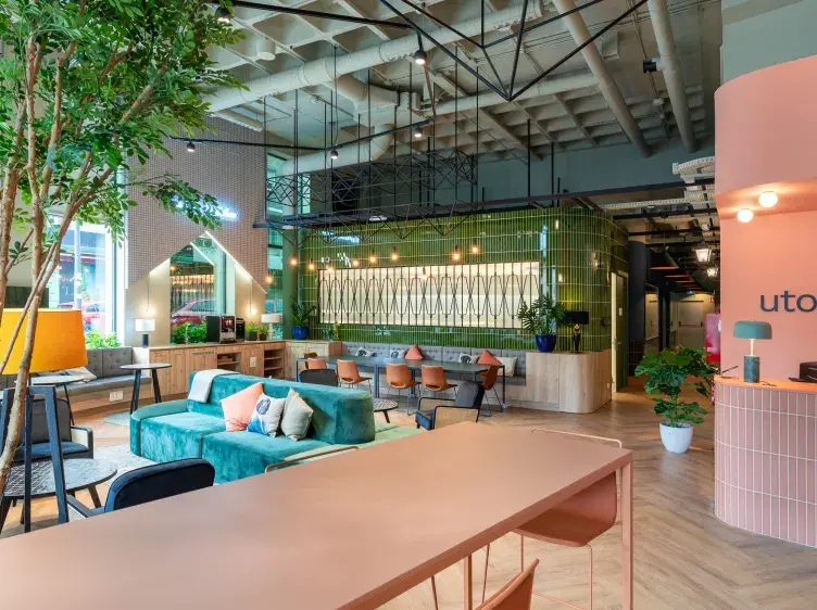 Espacio moderno con muebles coloridos y vegetación, incluye sofás, sillas y mesas en un ambiente iluminado.
