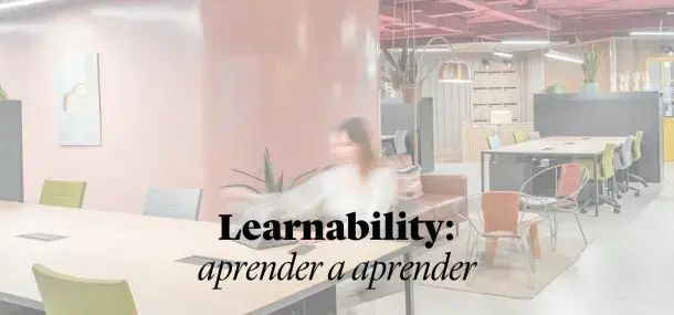Una persona sentada en una oficina moderna con paredes rosas y sillas de colores.